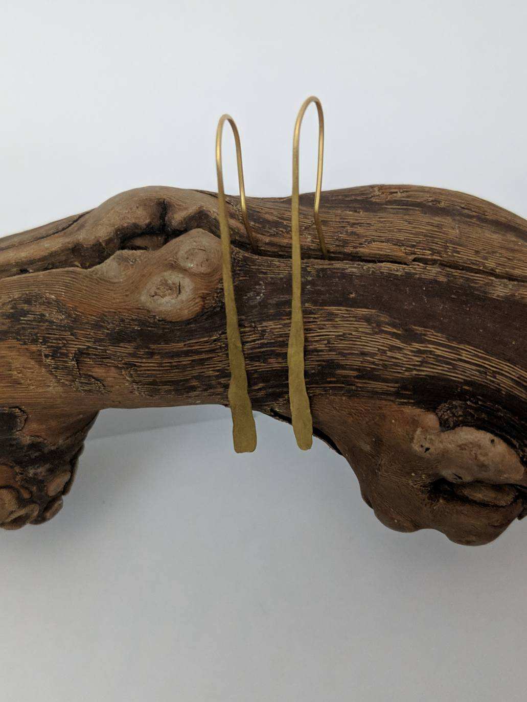 Long gold-toned drop earrings displayed on wood