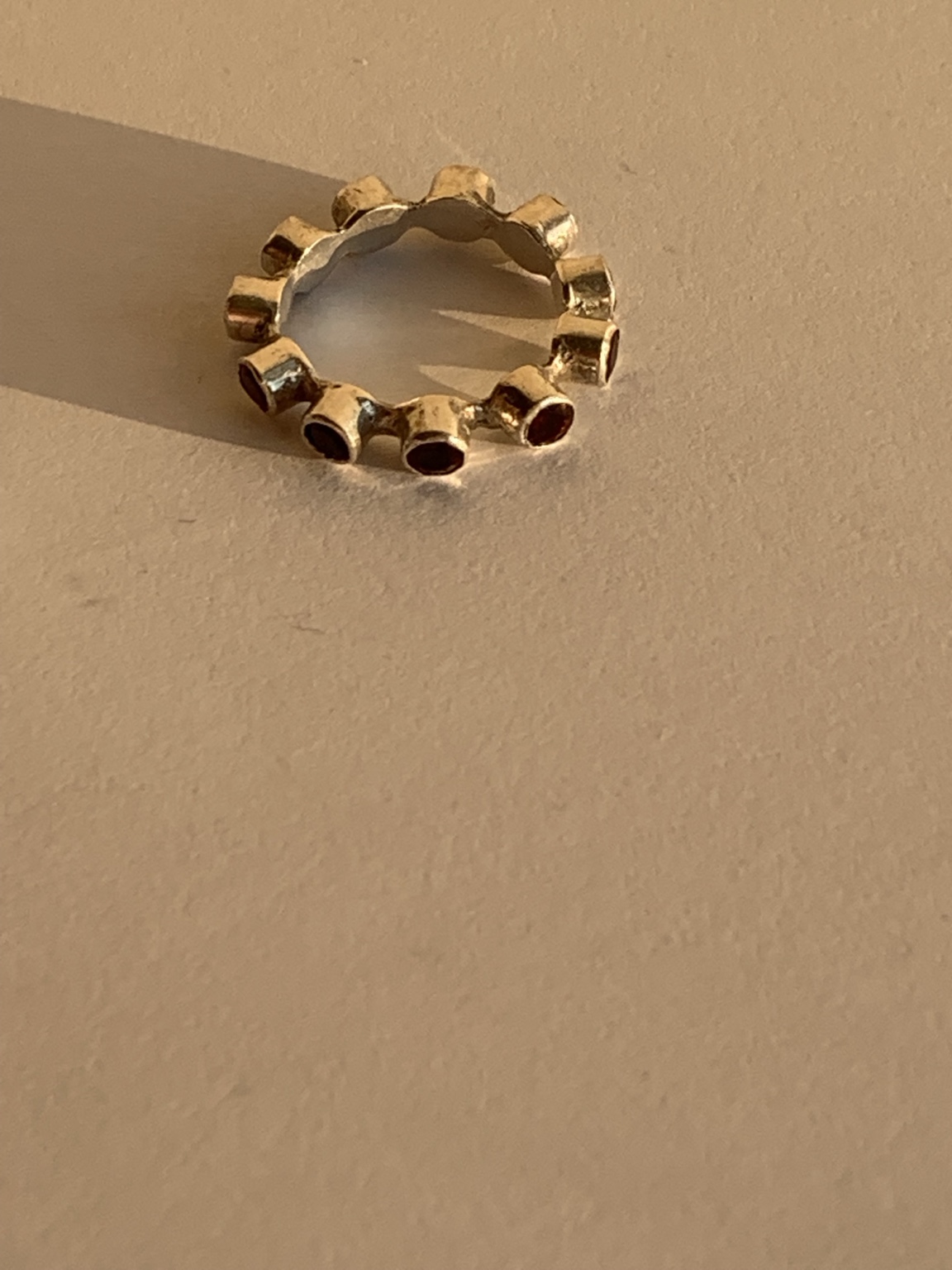 Scalloped ring with a circle of deep red stones in raised settings