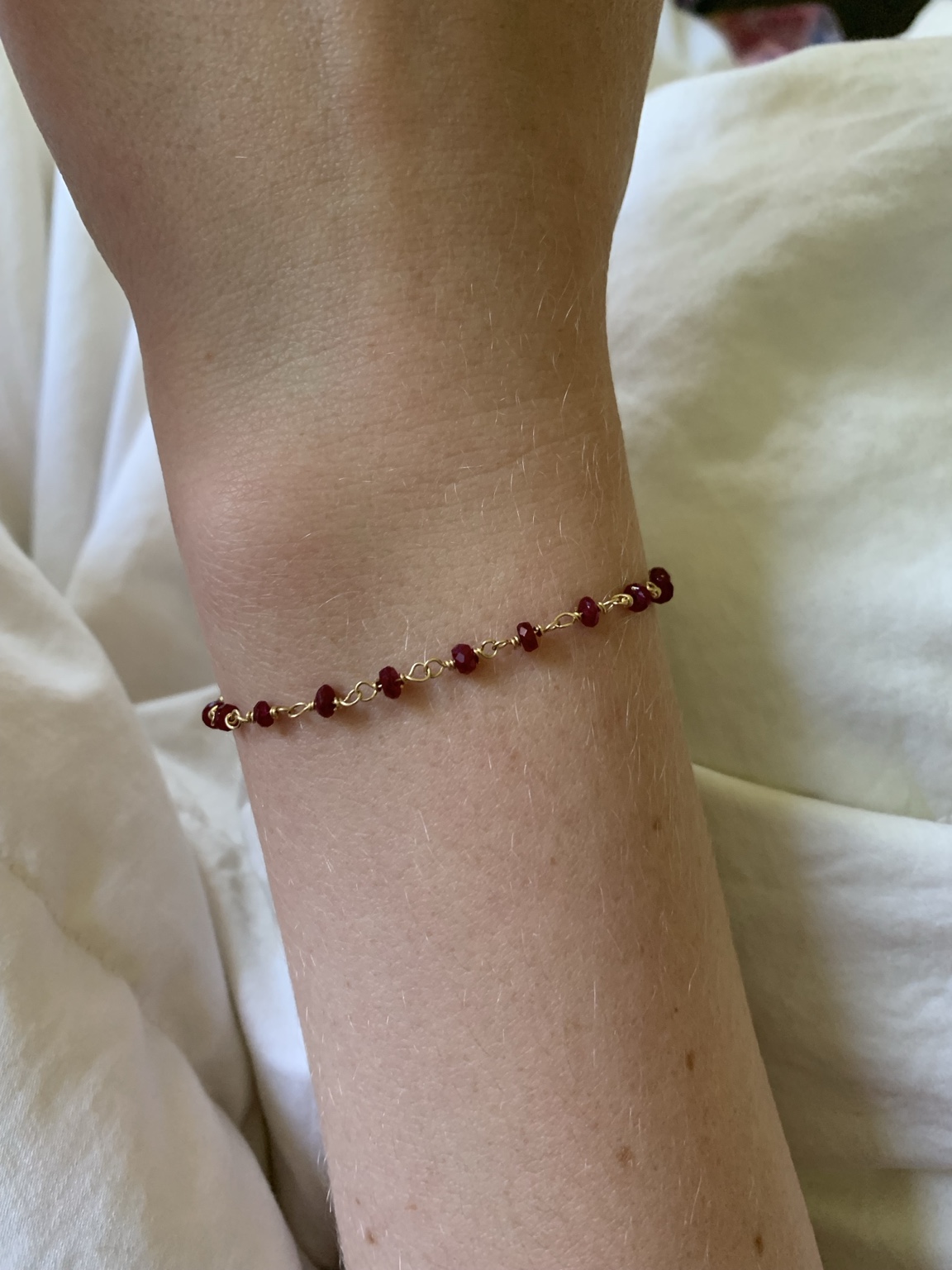 Ruby and gold bracelet worn on a wrist