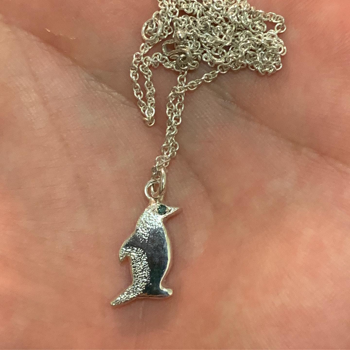 Penguin pendant with a blue diamond eye on a chain