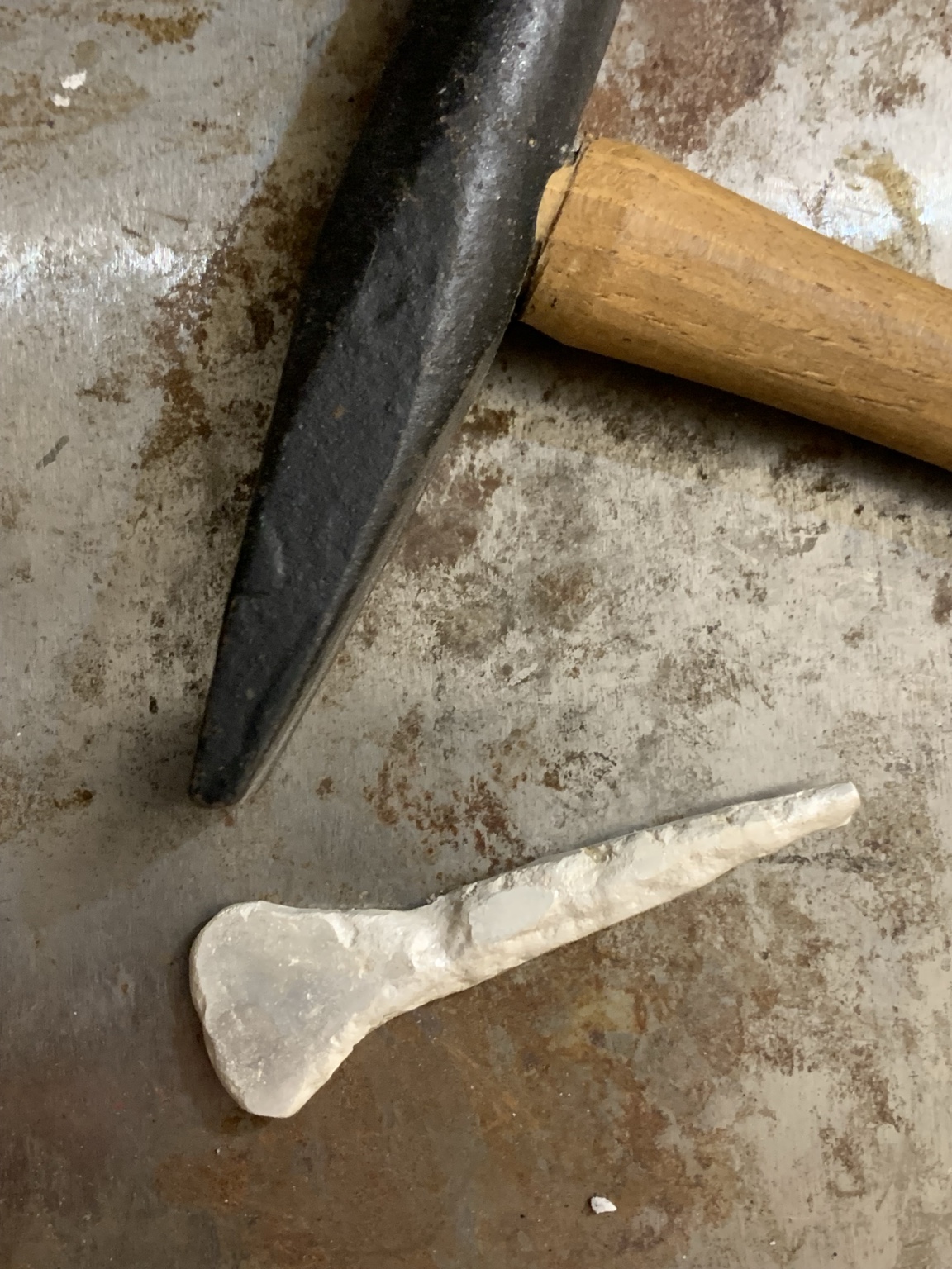 Newly formed metal element beside a hammer