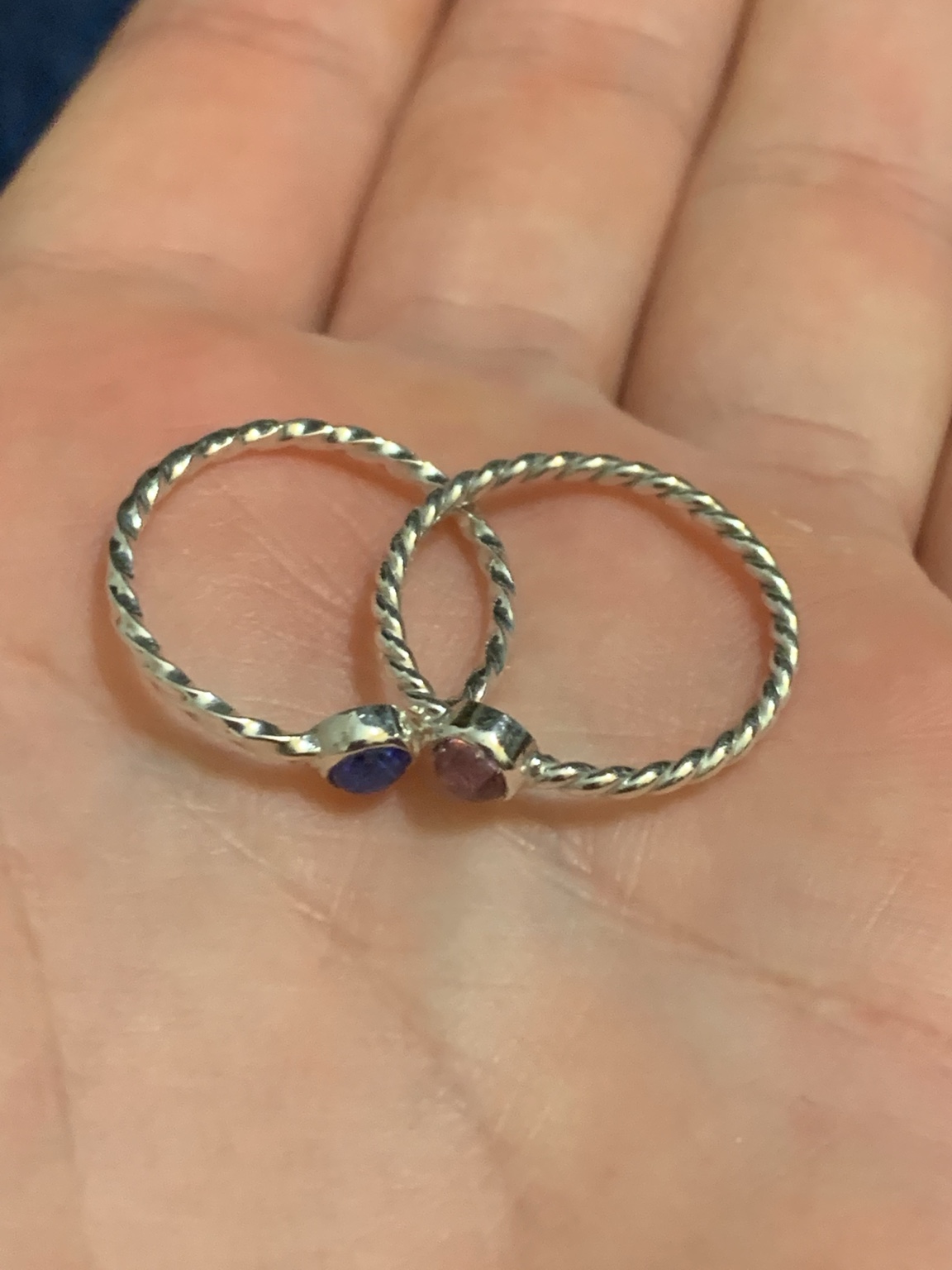 Two twisted metal rings with small colorful stones